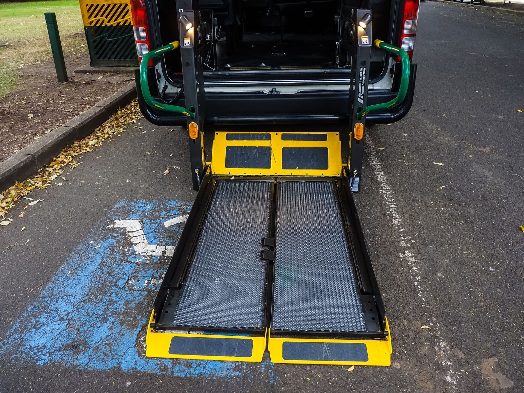 Wheelchair lift platform lowered at the rear of a wheelchair-accessible taxi