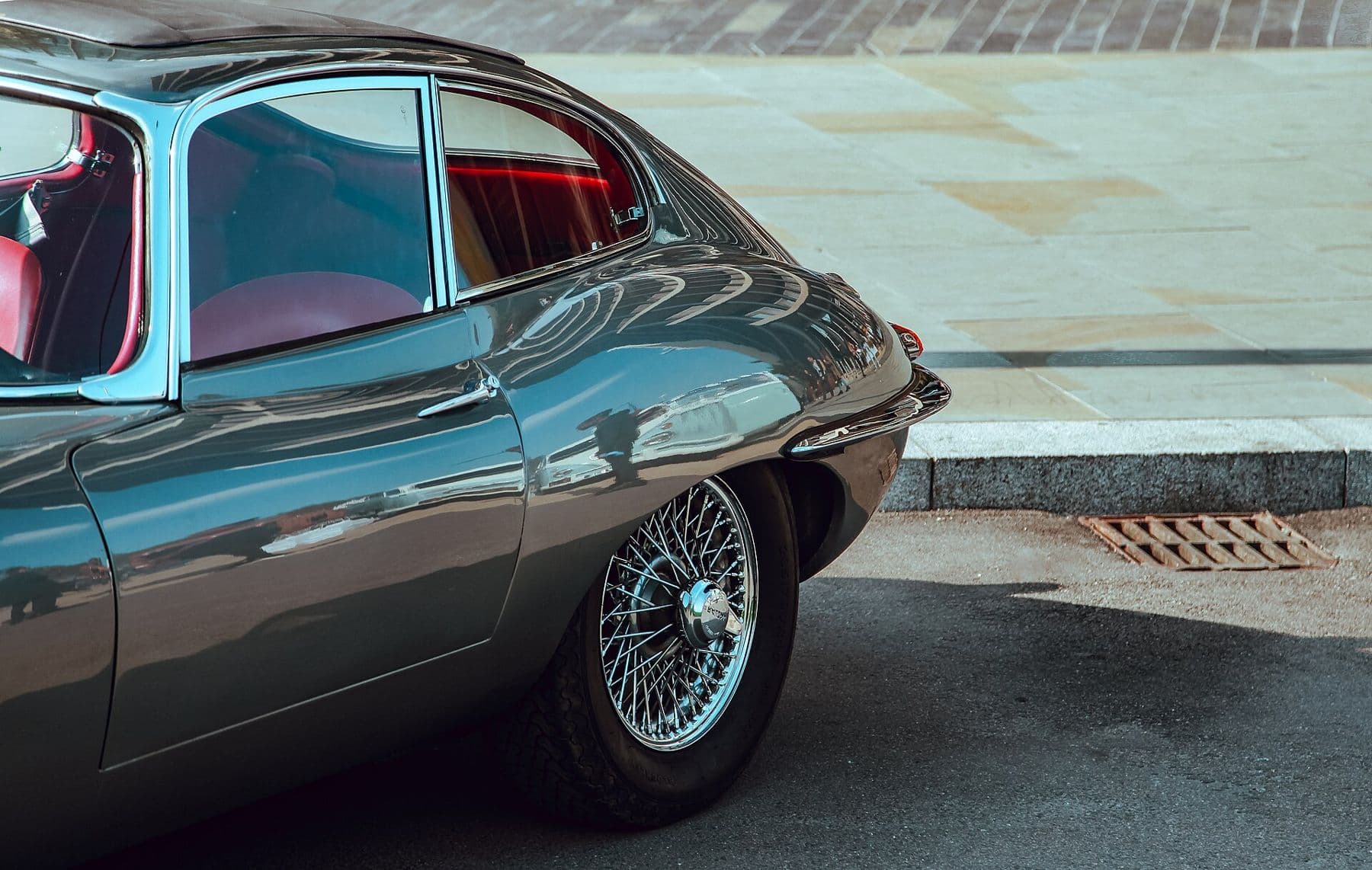 Classic Jaguar E-Type coupe with red leather interior parked on a paved street