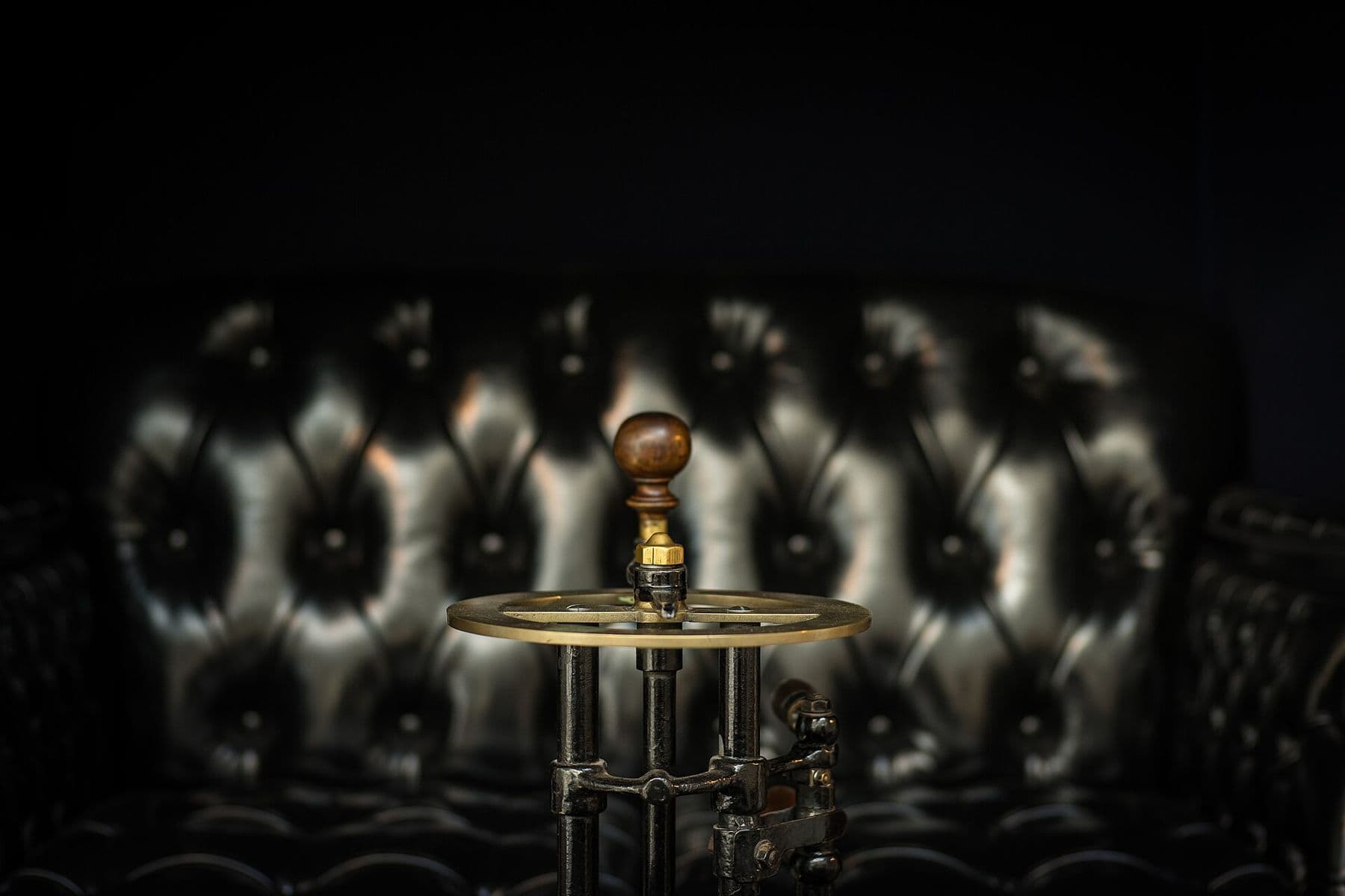 Deep-buttoned, diamond-tufted black leather upholstery lit against a dark background